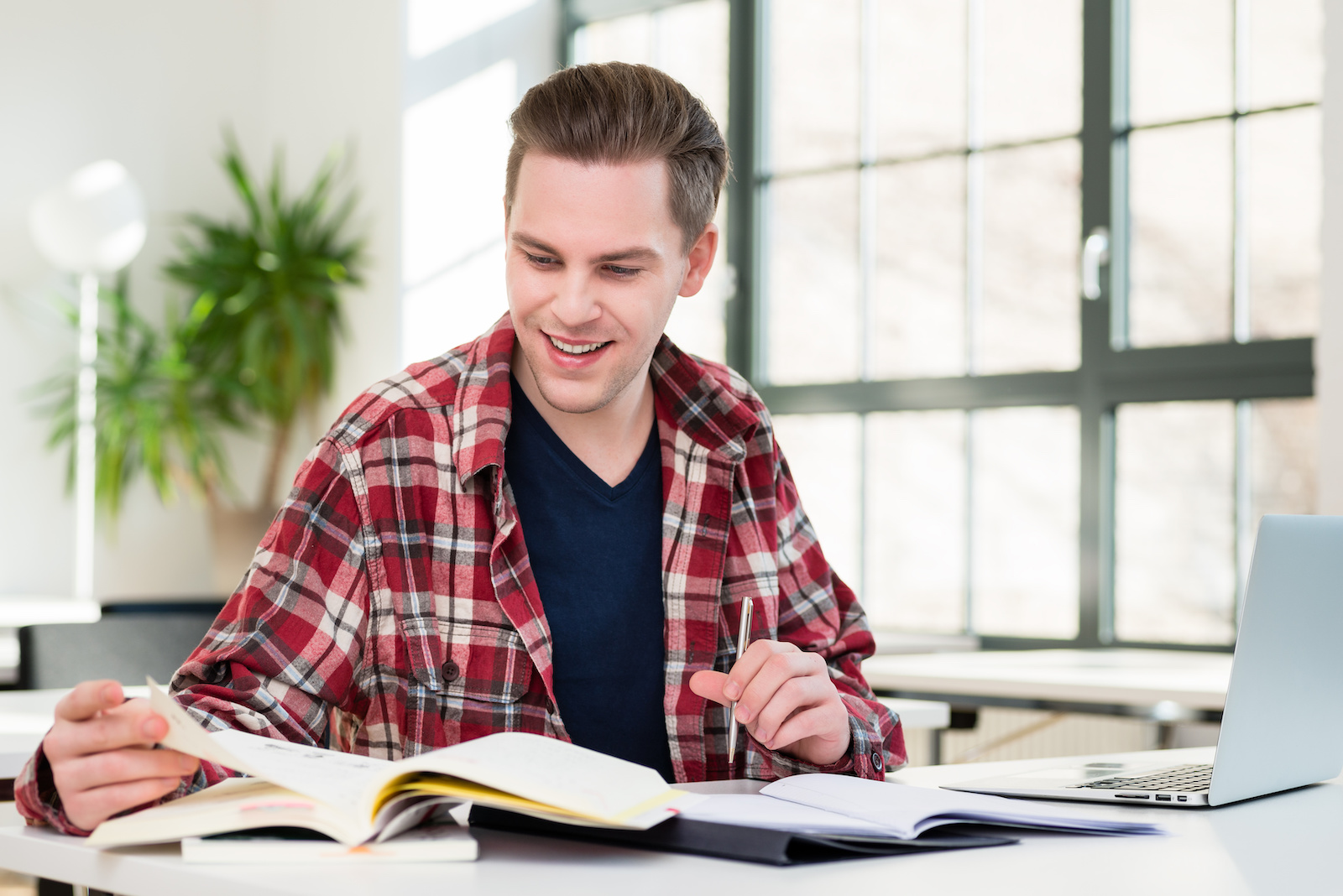 Portrait of a young student smiling while researching information for an interesting essay at desk in the classroom of a modern university